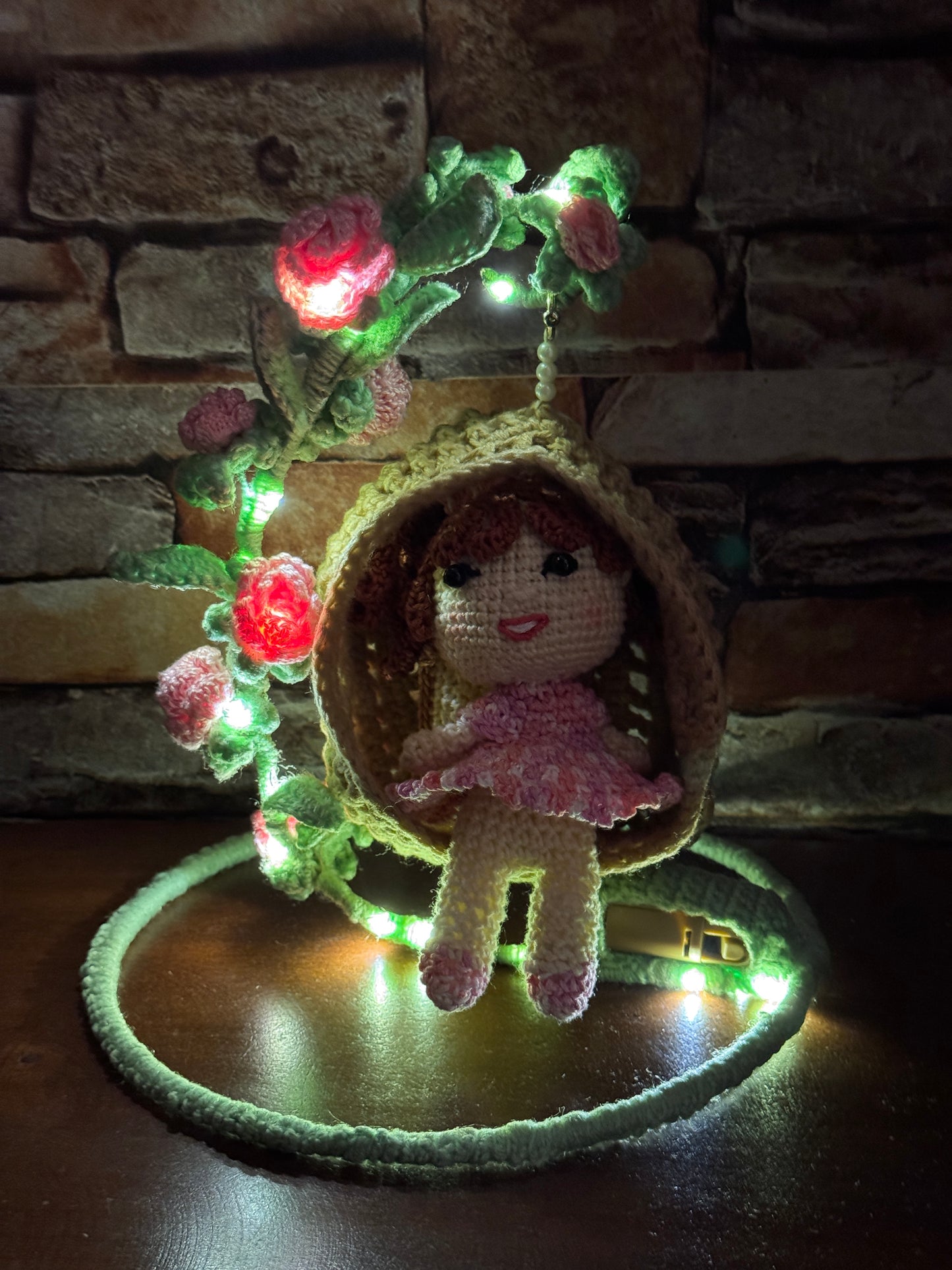 Girl in a swing adorned with flowers - handcrafted crochet decor with LED lights