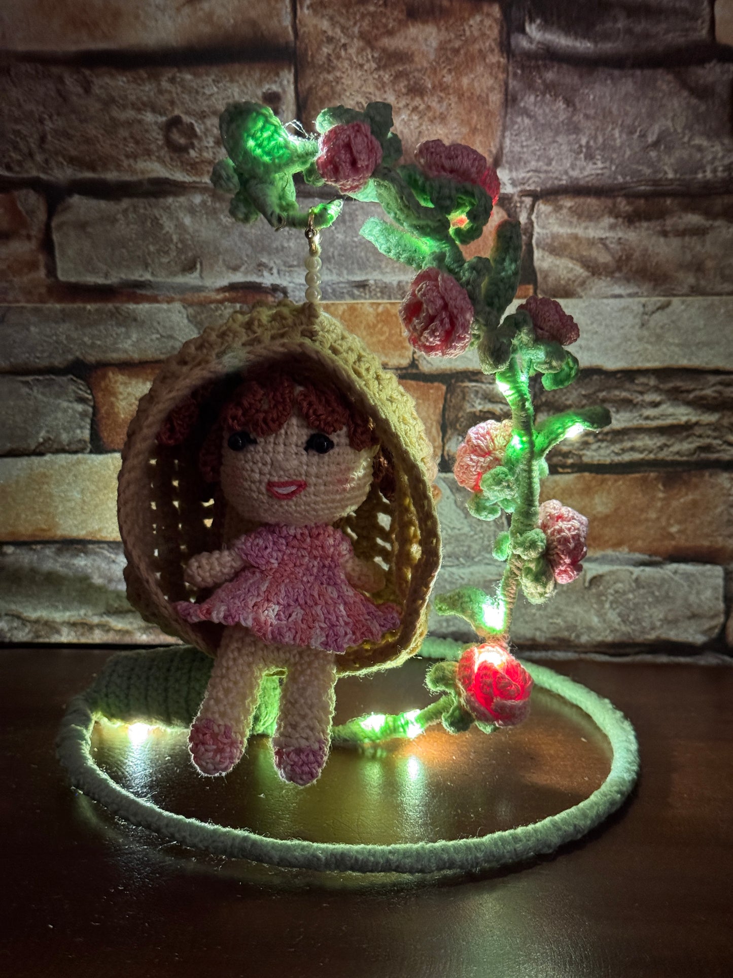 Girl in a swing adorned with flowers - handcrafted crochet decor with LED lights