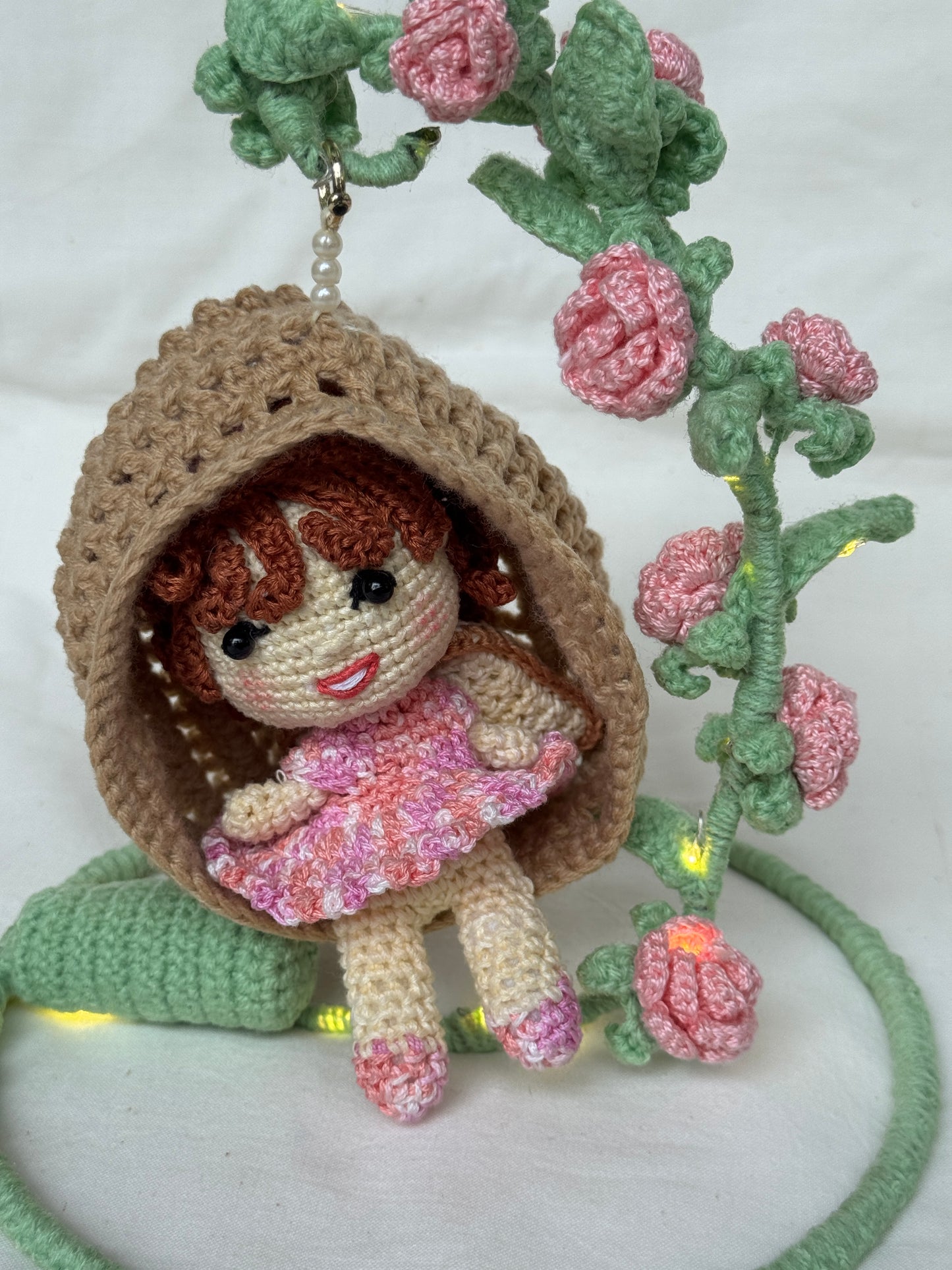 Girl in a swing adorned with flowers - handcrafted crochet decor with LED lights