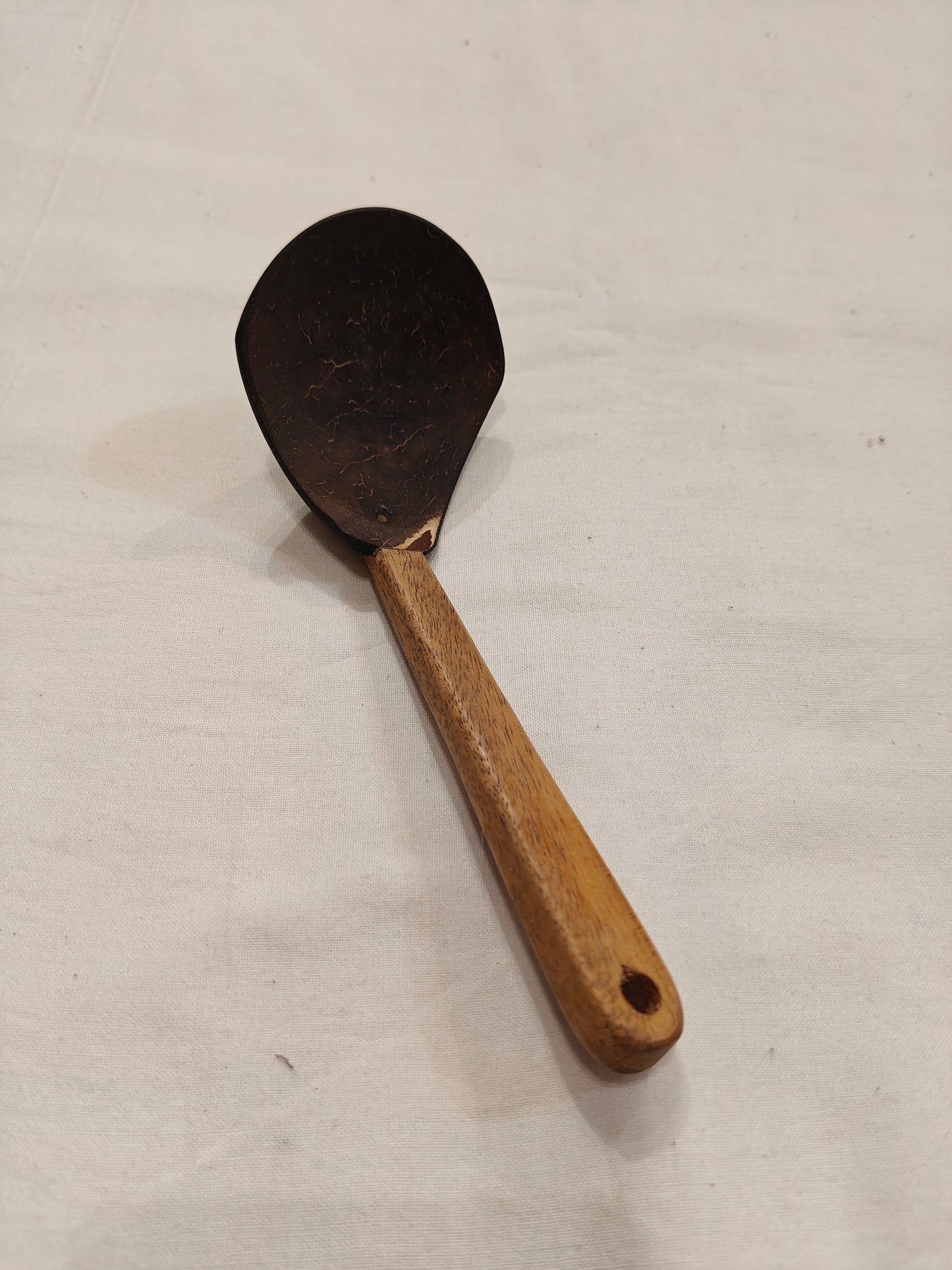 Serving spoon made of coconut shell with wooden handle
