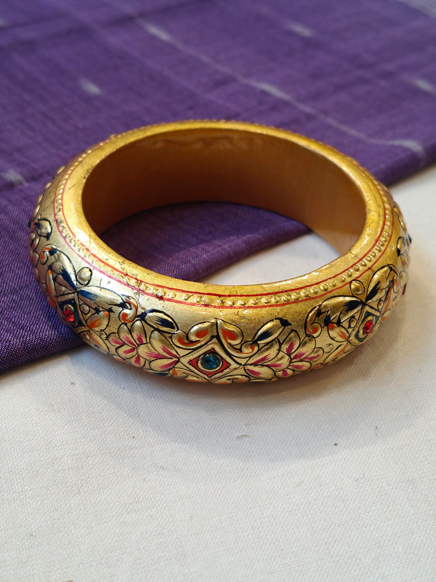 Single gold embossed wide bangle with blue and red stones