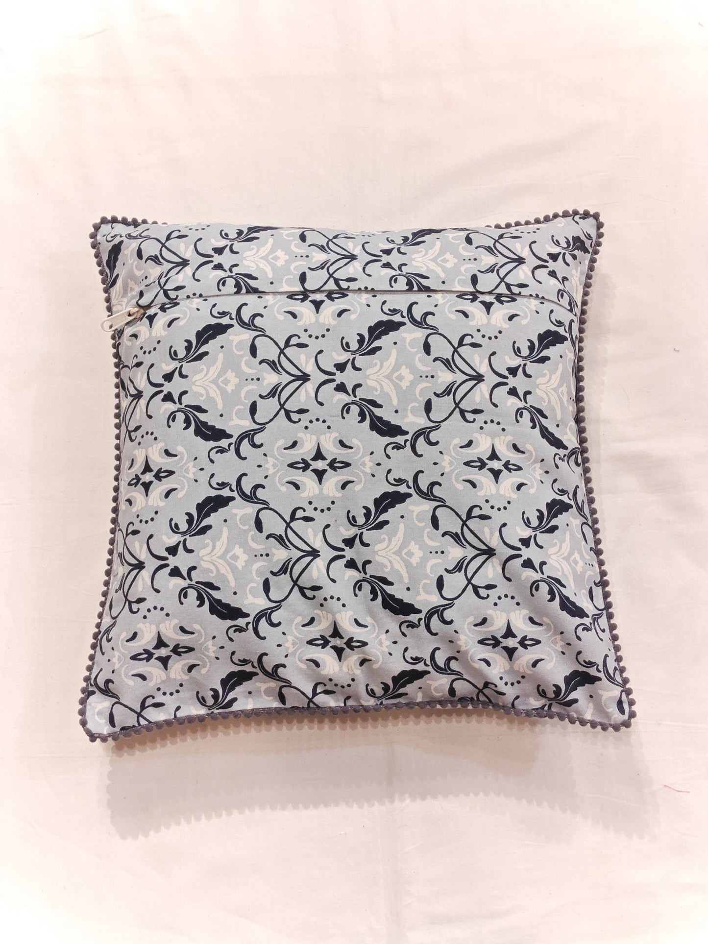 Cushion cover with blue and white patterns and pom pom borders
