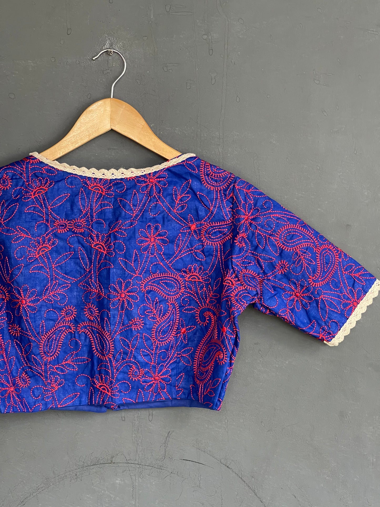Red floral embroidery on blue blouse with lace