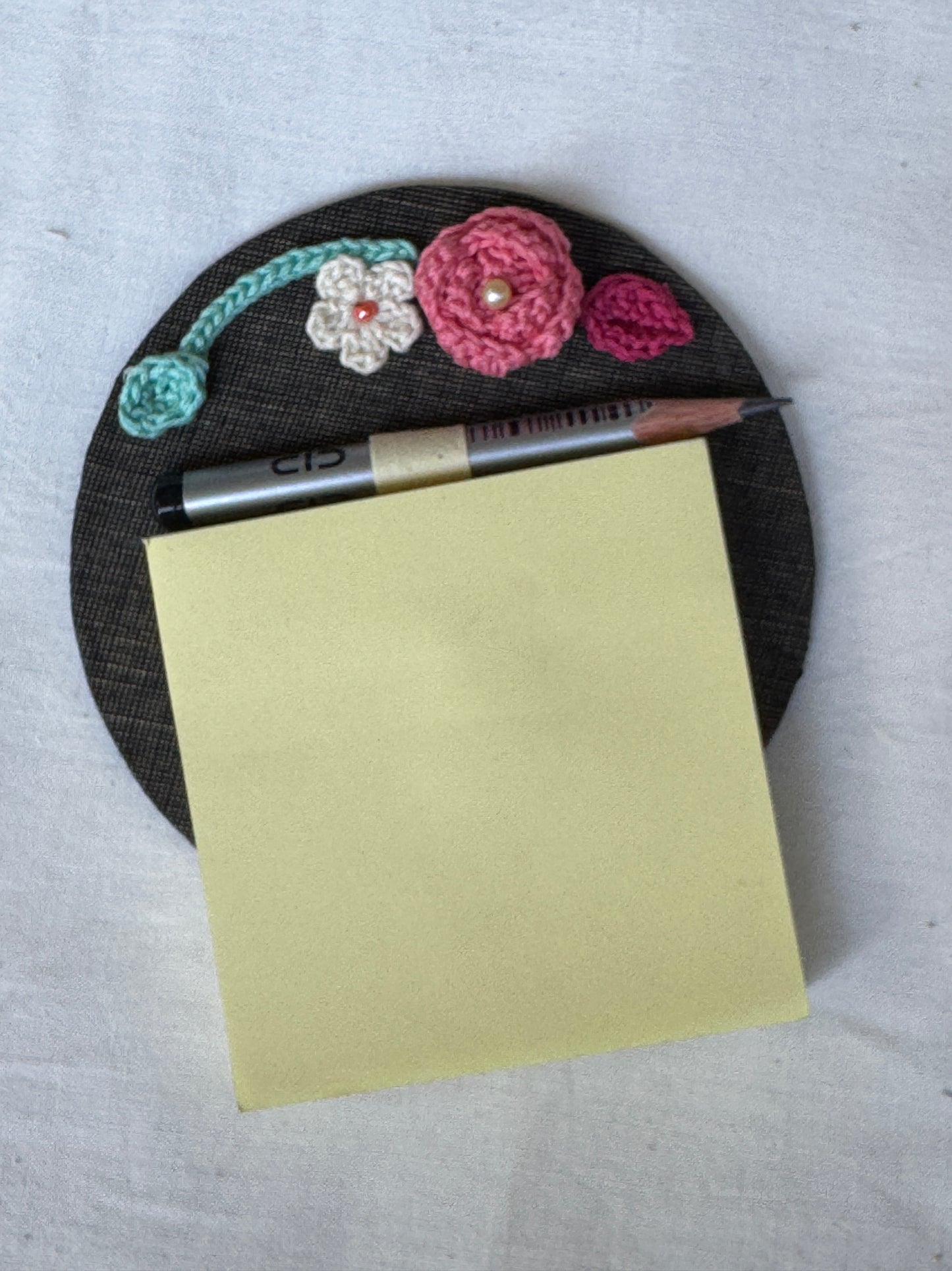Round fridge magnet with crochet detailing to keep your shopping / to-do list handy