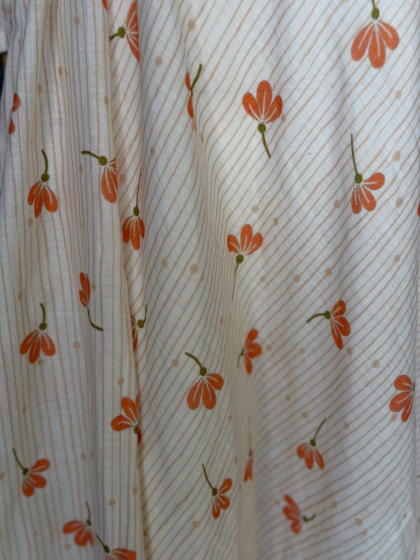 Peach floral print on off white soft cotton umbrella dress with band collared neck, long sleeves and waist belt
