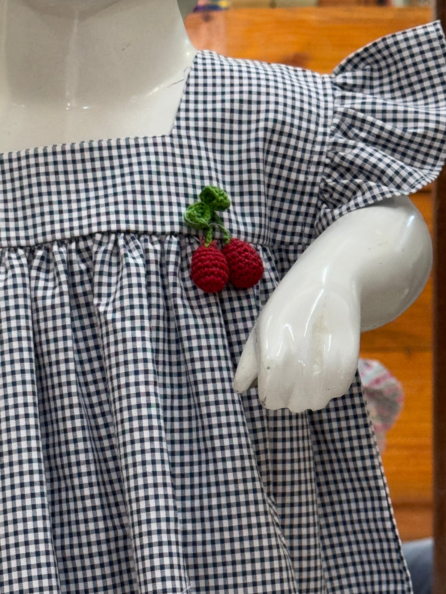 Black and white checks cotton baby frock with red cherries embroidery, crochet brooch