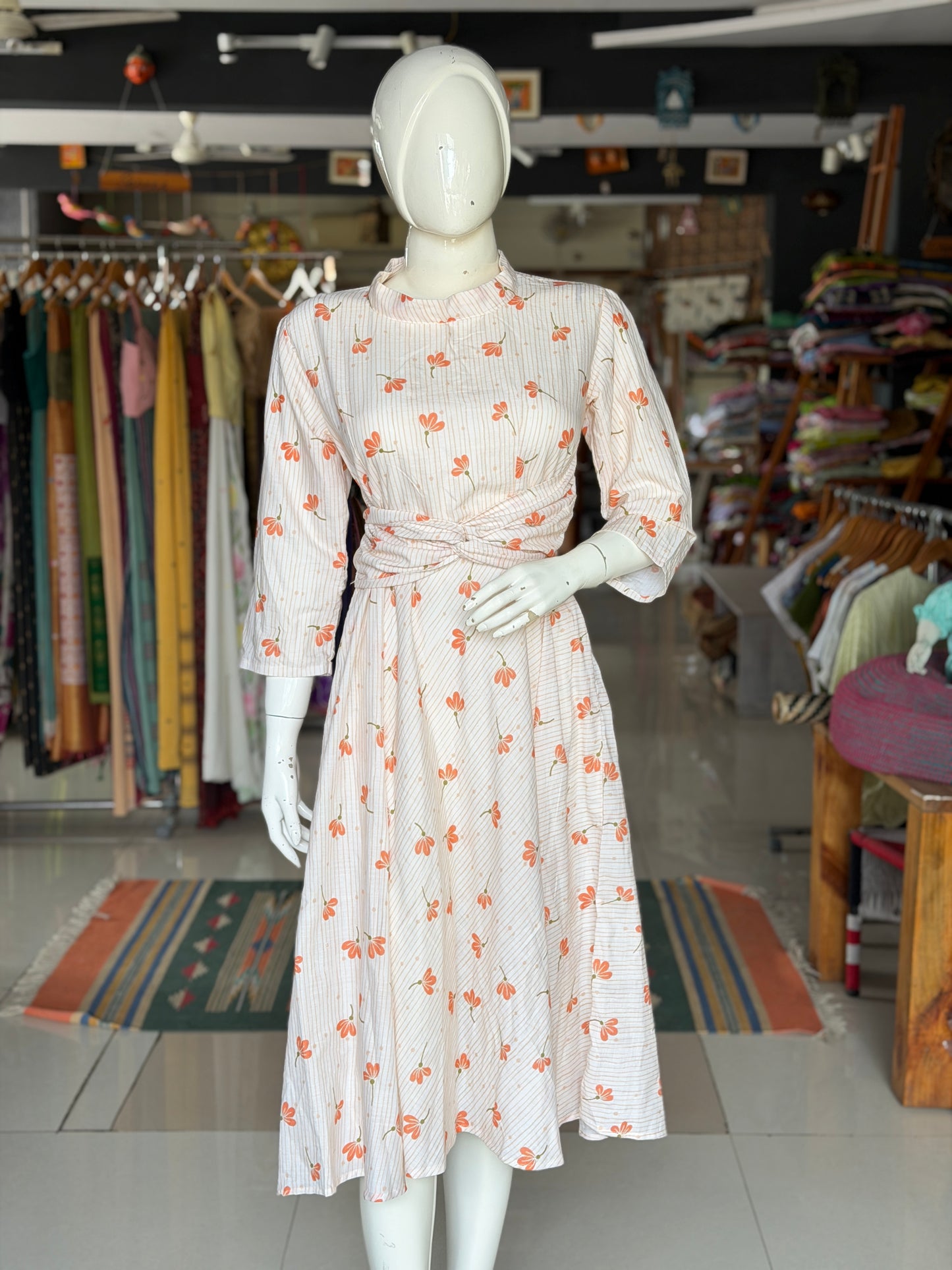 Peach floral print on off white soft cotton umbrella dress with band collared neck, long sleeves and waist belt