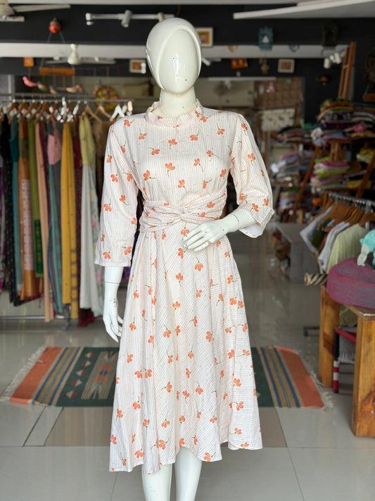 Peach floral print on off white soft cotton umbrella dress with band collared neck, long sleeves and waist belt