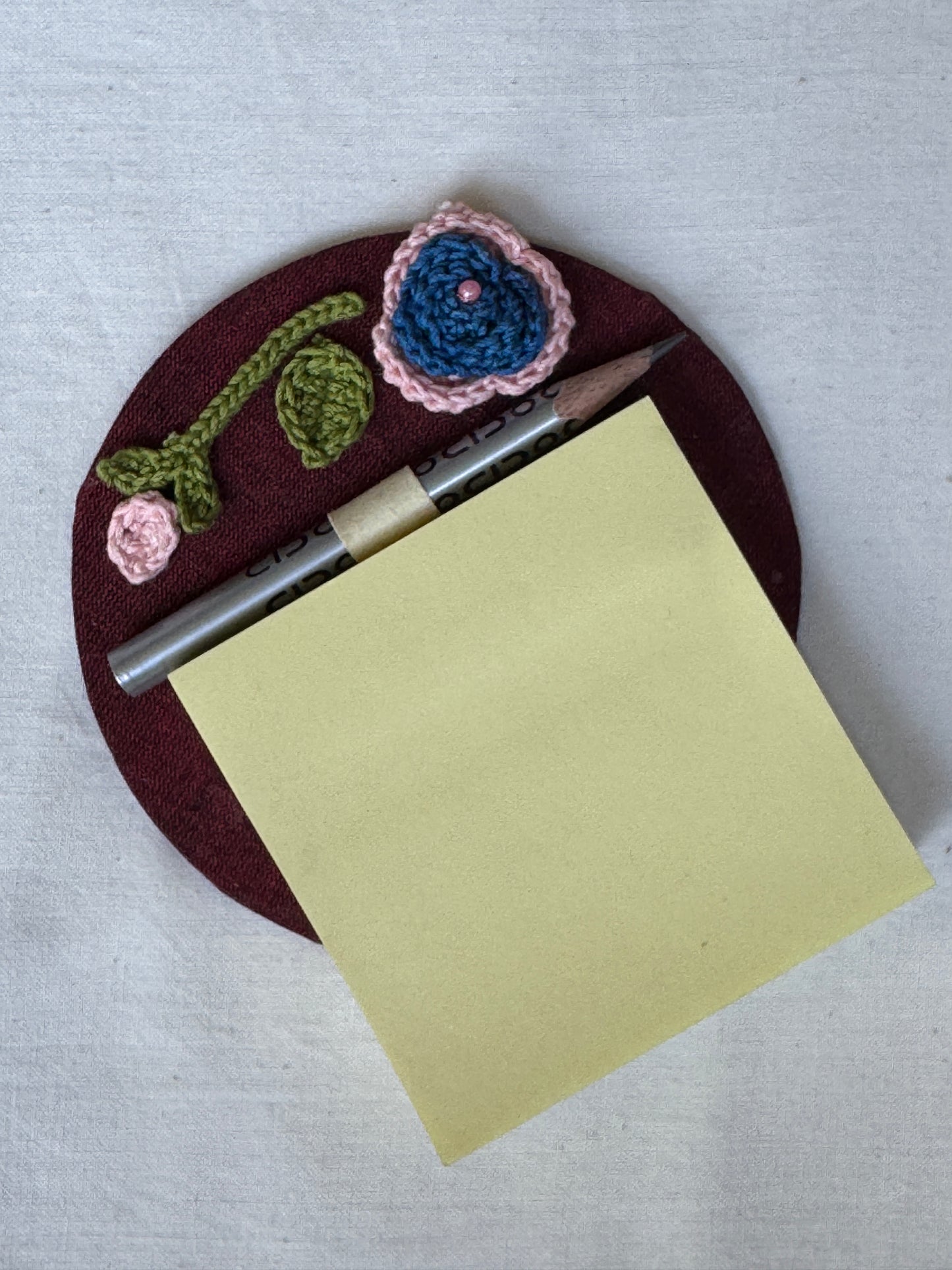 Round fridge magnet with crochet detailing to keep your shopping / to-do list handy