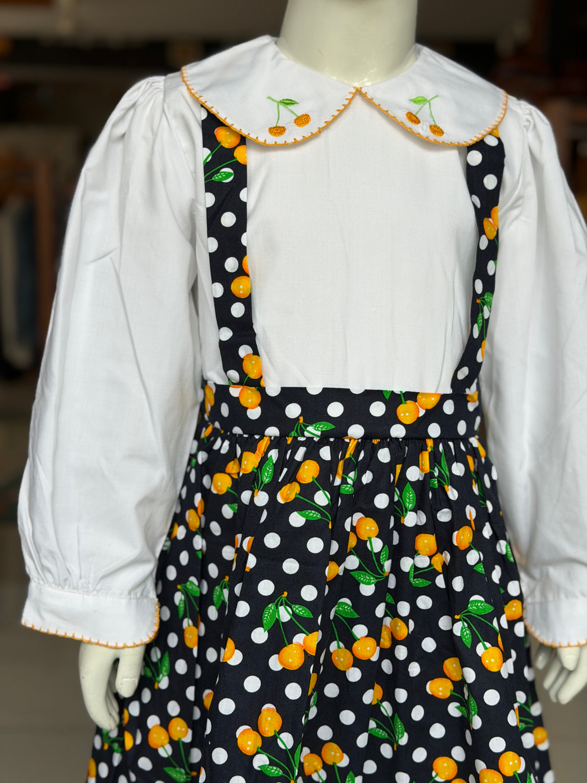 Black polka dots and cherries printed suspender look cotton frock with attached white  embroidered collared top for girls