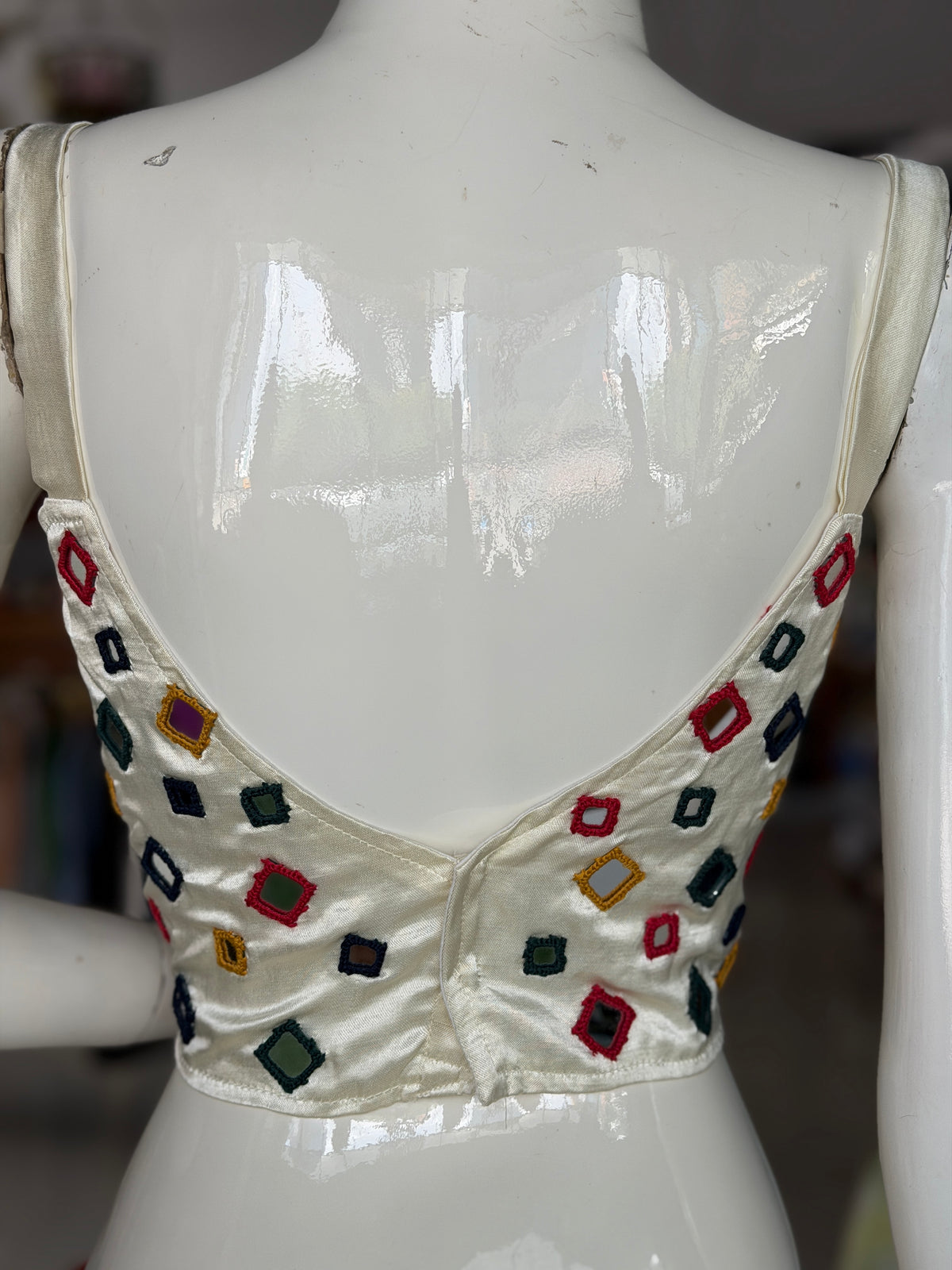 Off white mashru sleeveless blouse with all over colorful mirror work on front and back