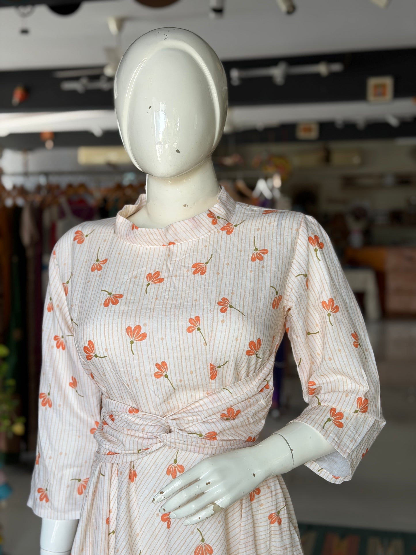 Peach floral print on off white soft cotton umbrella dress with band collared neck, long sleeves and waist belt