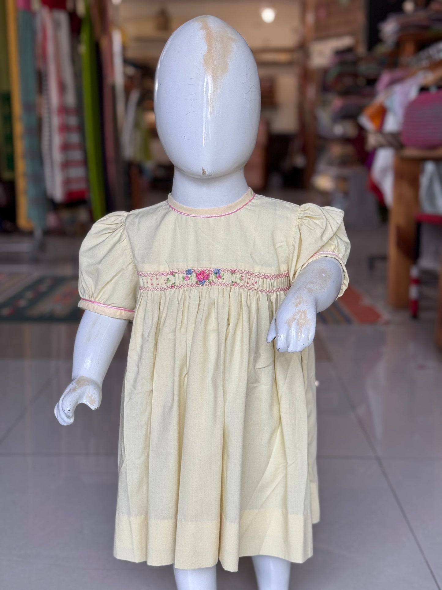 Light yellow hand embroidered smocking cotton frock for girls with piping at neck line