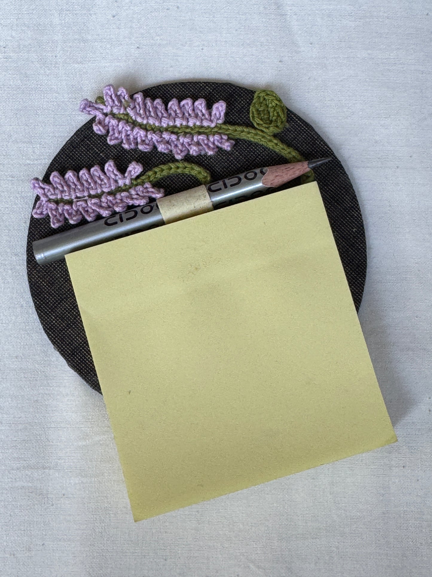 Round fridge magnet with crochet detailing to keep your shopping / to-do list handy