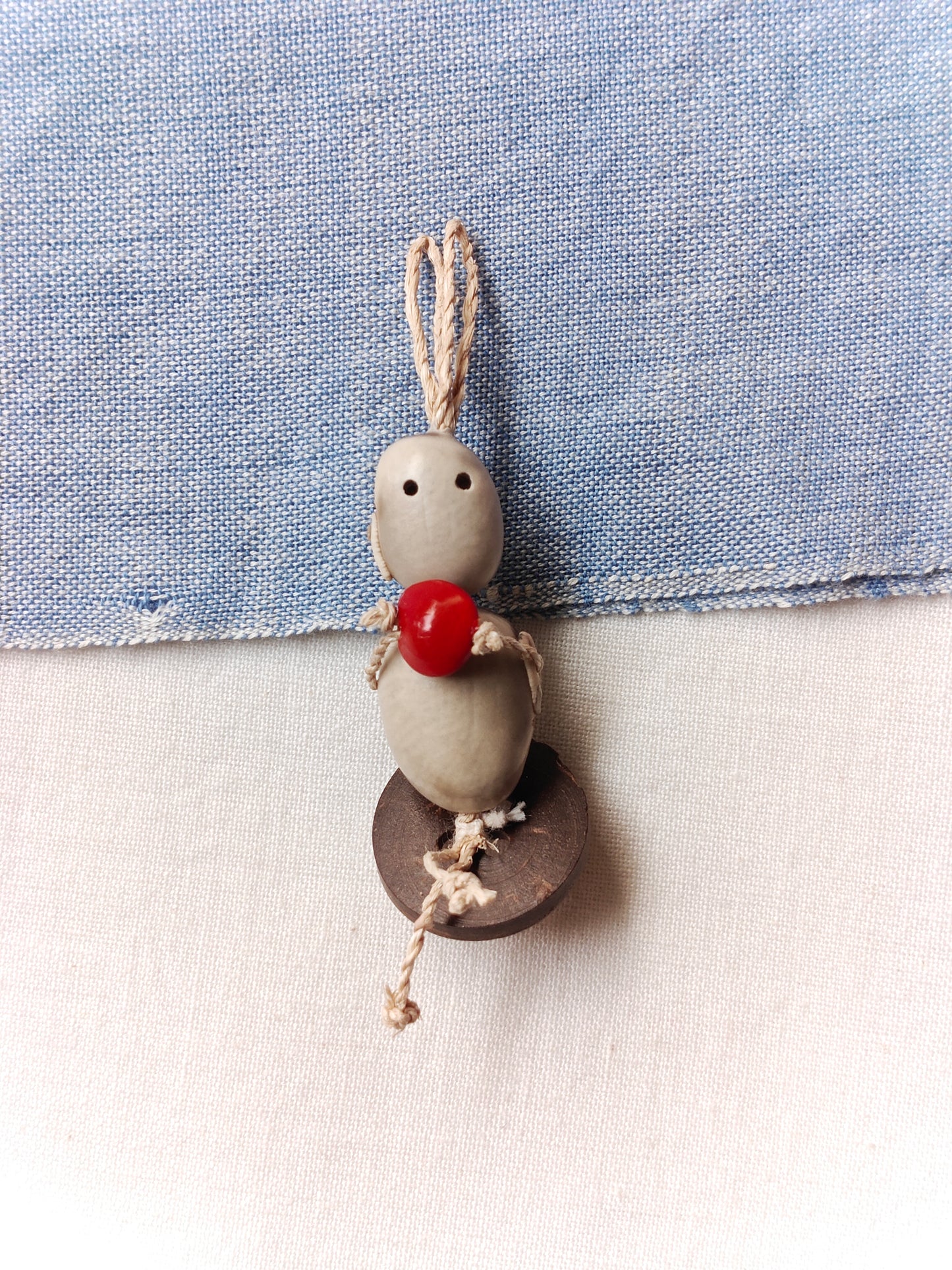 Sitting doll hanging holding a red seed- Hancrafted with seeds