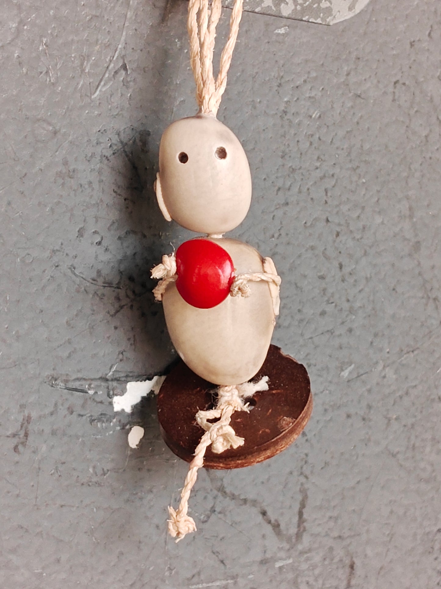 Sitting doll hanging holding a red seed- Hancrafted with seeds