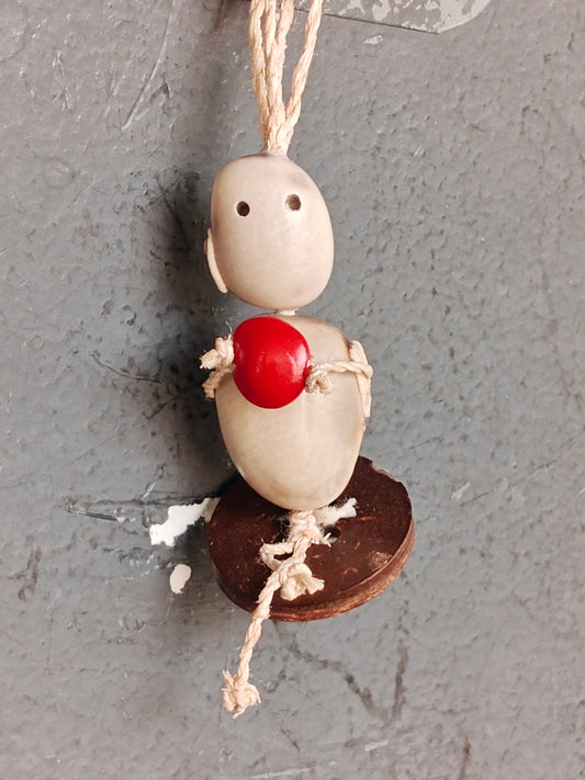 Sitting doll hanging holding a red seed- Hancrafted with seeds