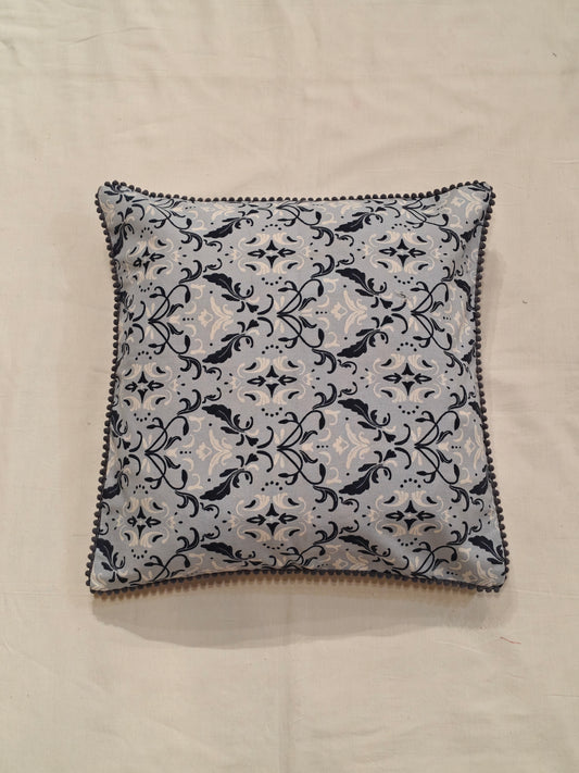 Cushion cover with blue and white patterns and pom pom borders