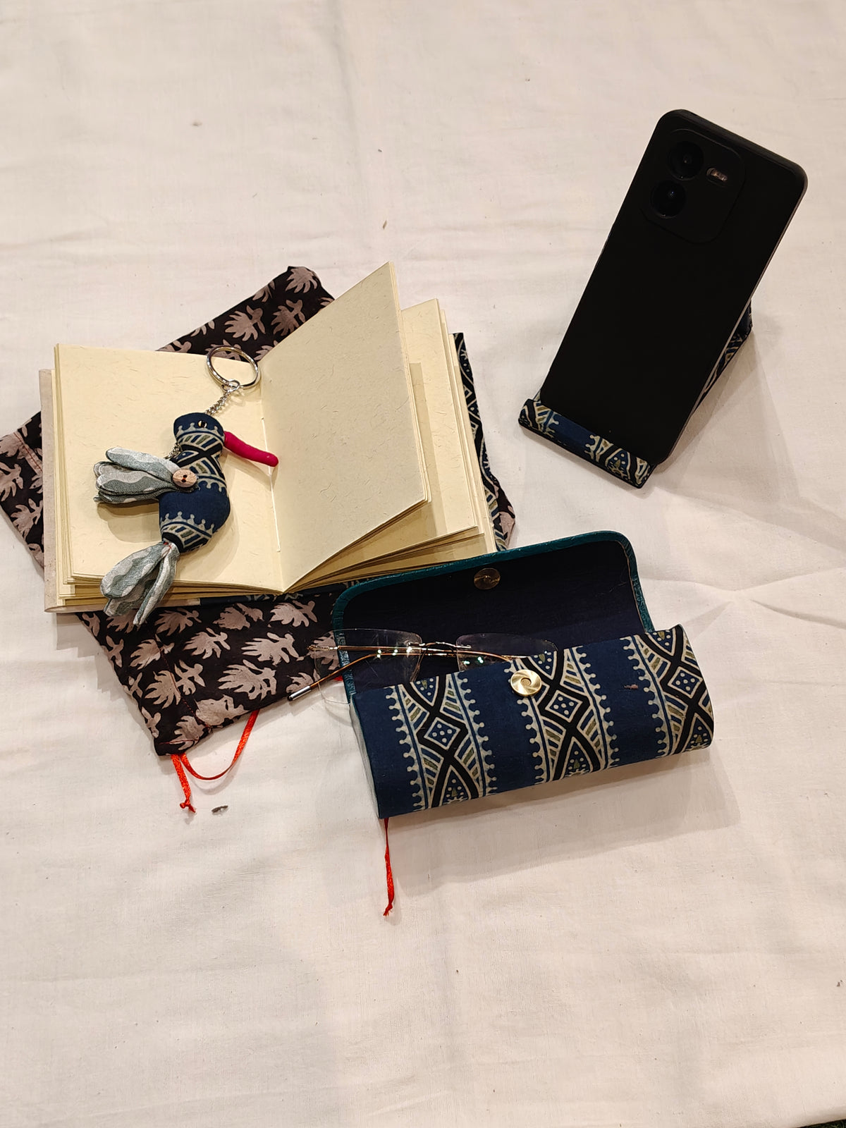 Handmade paper notebook with eco leaf printed fabric cover, bird design key ring / bag charm, mobile stand, spectacles box and a potli - gift set