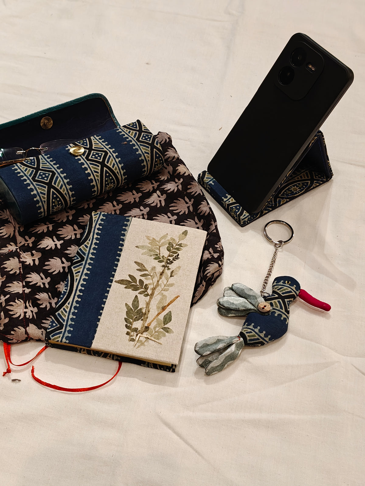 Handmade paper notebook with eco leaf printed fabric cover, bird design key ring / bag charm, mobile stand, spectacles box and a potli - gift set