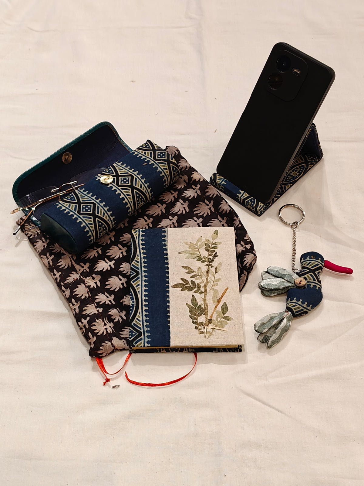 Handmade paper notebook with eco leaf printed fabric cover, bird design key ring / bag charm, mobile stand, spectacles box and a potli - gift set