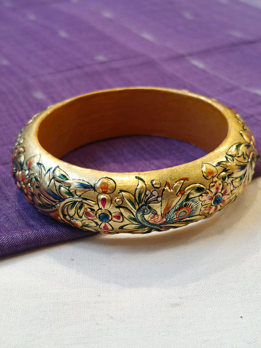 Single gold embossed wide bangle with peacock design and blue stones