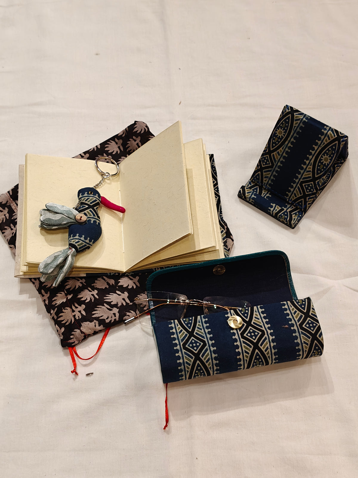 Handmade paper notebook with eco leaf printed fabric cover, bird design key ring / bag charm, mobile stand, spectacles box and a potli - gift set