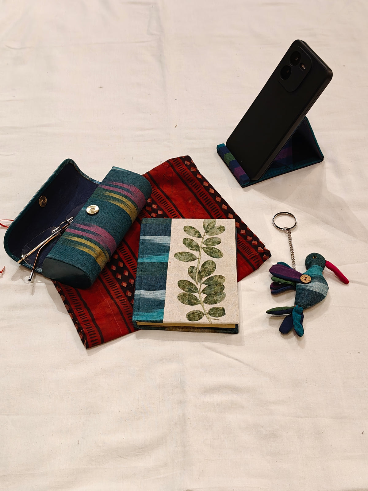 Handmade paper notebook with eco leaf printed fabric cover, bird design key ring / bag charm, mobile stand, spectacles box and a potli - gift set