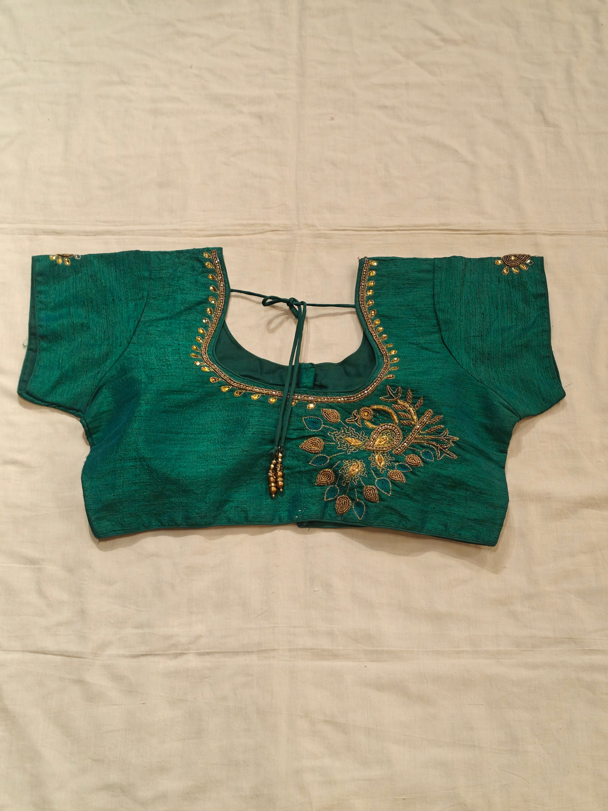 Green short sleeved blouse with beaded embroidery along the neckline and sleeves with peacock motif on back