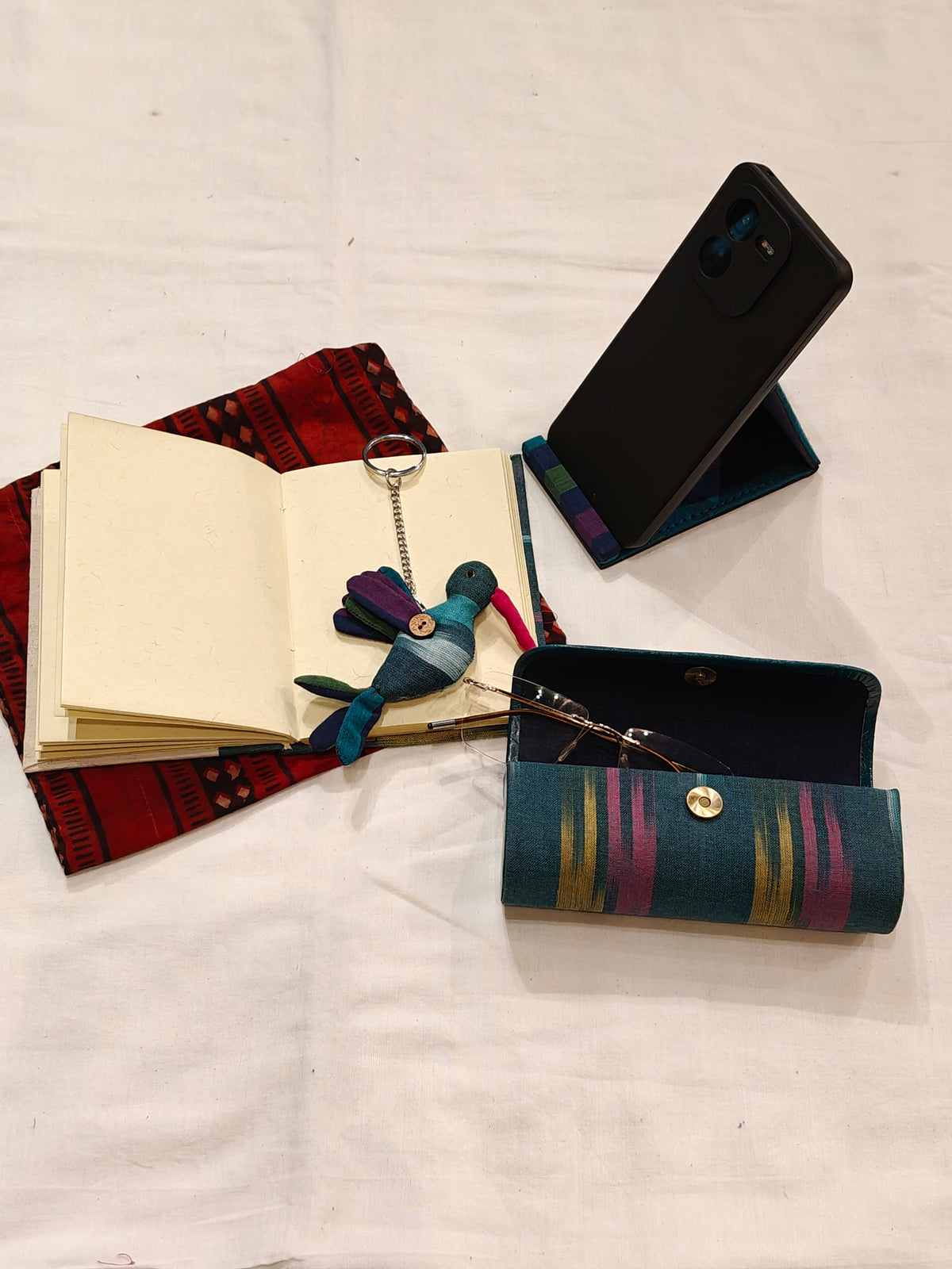 Handmade paper notebook with eco leaf printed fabric cover, bird design key ring / bag charm, mobile stand, spectacles box and a potli - gift set