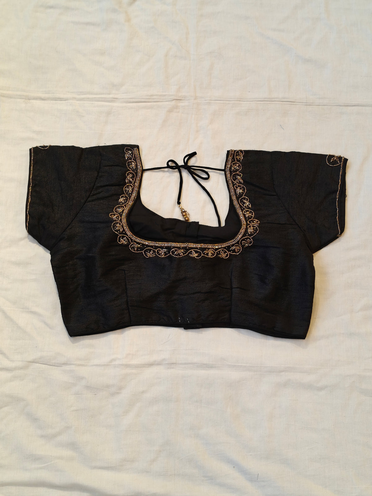 Black short sleeved blouse with beaded embroidery along the neckline and sleeves